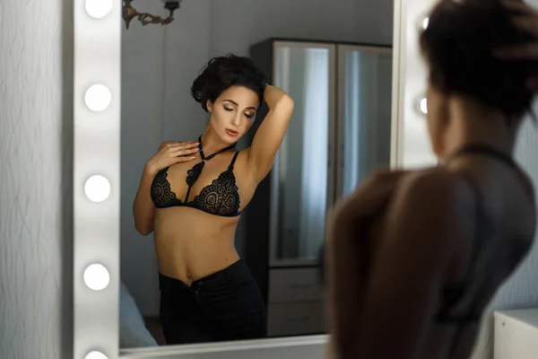 Σέξι όμορφη γυναίκα σε μαύρη δαντέλα εσώρουχα με μαύρο τζιν θέτει κοντά στον vintage καθρέφτη με λαμπτήρες — Φωτογραφία Αρχείου