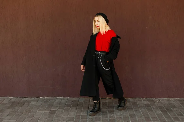 Mooie jonge vrouw in een stijlvolle trendy jas in de herfst dag in de buurt van de muur — Stockfoto