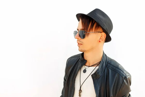 Perfil de um jovem homem bonito com chapéu de óculos de sol em jaqueta preta no fundo branco — Fotografia de Stock