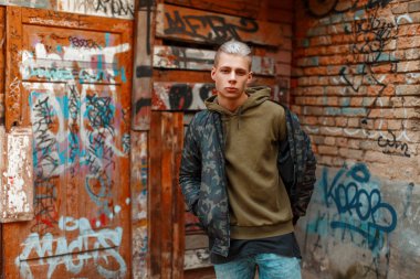 yakışıklı genç adam sokakta bir duvarının yakınında şık askeri ceket