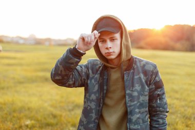 Bir ordu ceket doğada günbatımında bir kapaklı şık yakışıklı genç adam