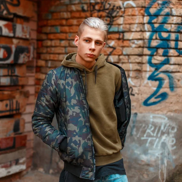 Ung snygg man i militära Modekläder nära en vägg — Stockfoto