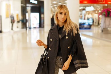 Alışveriş merkezine şık bir çanta trendy gri paltolu şık genç kadın