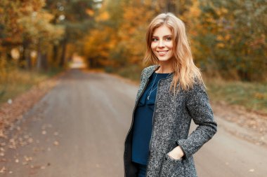 Güzel neşeli kadın parkta trendy şık paltolu bir gülümsemeyle