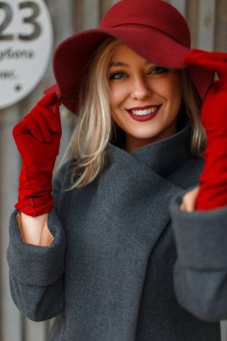 Mutlu genç kadın şık bir şapka ve şık bir gri ceket bir gülümseme. İyi bir ruh hali