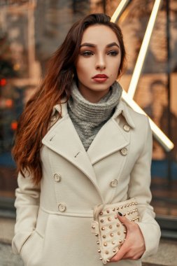 Son moda bej bir palto bir vitrin poz şık bir çanta ile şık genç kadın