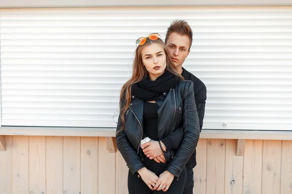 Hermosa pareja joven en un abrazo en ropa de moda con estilo cerca de la pared blanca — Foto de Stock