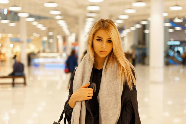 Красивая модная девушка в стильном пальто с шарфом в торговом центре — стоковое фото