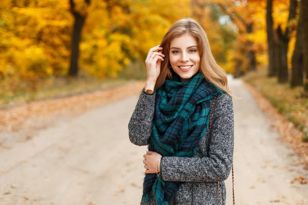 Stijlvolle gelukkige vrouw in trendy jas en sjaal wandelen in de herfst park — Stockfoto