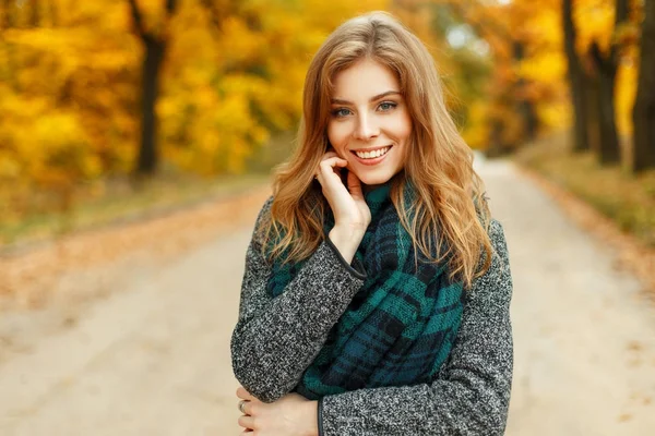 Schöne junge Frau mit einem Lächeln genießt das Herbstwetter in einem Park in der Nähe des gelben Laubes — Stockfoto