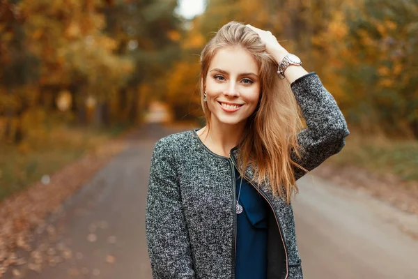 Щаслива красива жінка з посмішкою в осінньому стильному пальто позує в парку — стокове фото