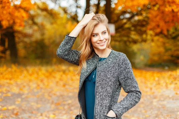 Mooie gelukkige vrouw in herfst stijlvolle kleding, genieten van het weer in de buurt van de gele bladeren — Stockfoto