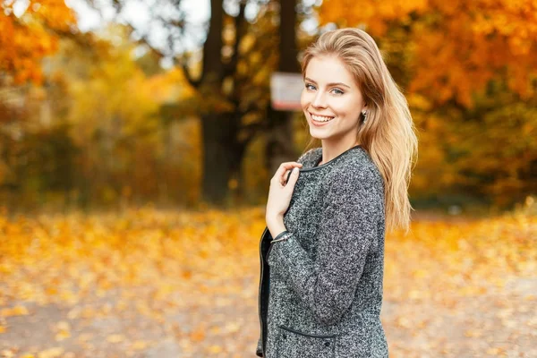 노란색가 공원 배경 유행 코트에 미소와 행복 한 여자 — 스톡 사진