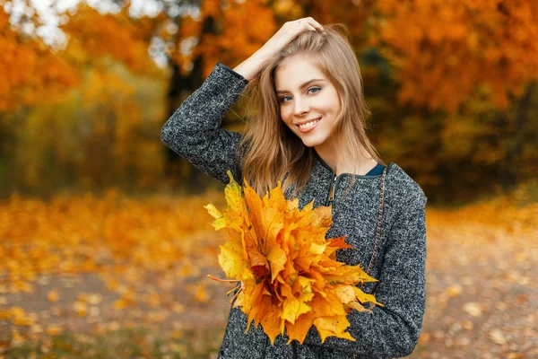 Mulher bonita feliz com um sorriso com flores amarelas de outono no parque — Fotografia de Stock