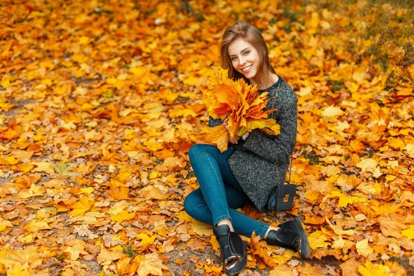 Belle femme heureuse avec un sourire dans un manteau à la mode profitant du moment dans le feuillage jaune d'automne. Bonne humeur — Photo