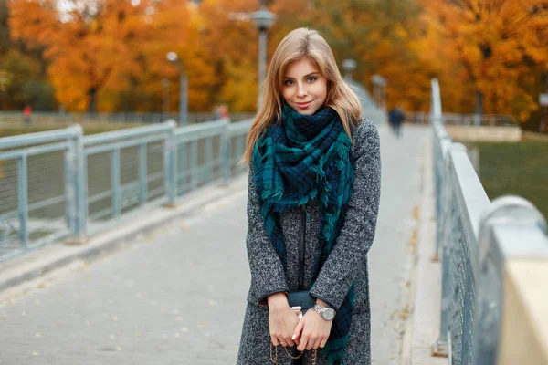 Happy beautiful woman in fashionable autumn clothes on bridge in autumn day — Stock Photo, Image