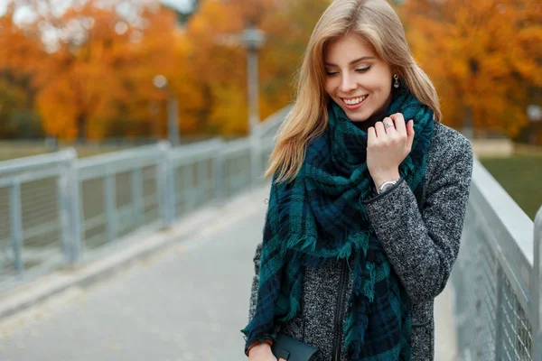 Glückliche Frau mit einem Lächeln im trendigen Herbstmantel mit stylischem Schal am Herbsttag auf der Straße — Stockfoto