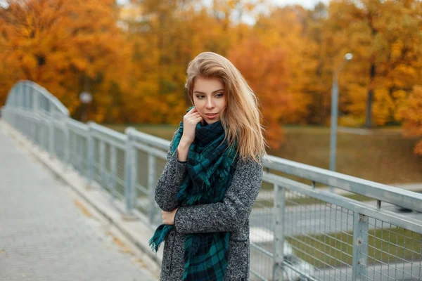 Joyeux belle femme en manteau à la mode avec écharpe sur le pont le jour d'automne — Photo