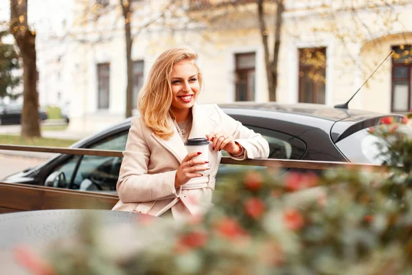 Felice ragazza con un sorriso beve caffè e si siede in un caffè per strada — Foto Stock