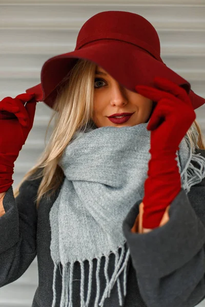 Красива молода жінка в модному капелюсі з сірим шарфом і стильним пальто позує біля дерев'яної стіни — стокове фото
