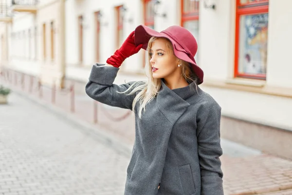 Élégante jeune femme avec chapeau de mode en manteau élégant gris posant dans la ville — Photo