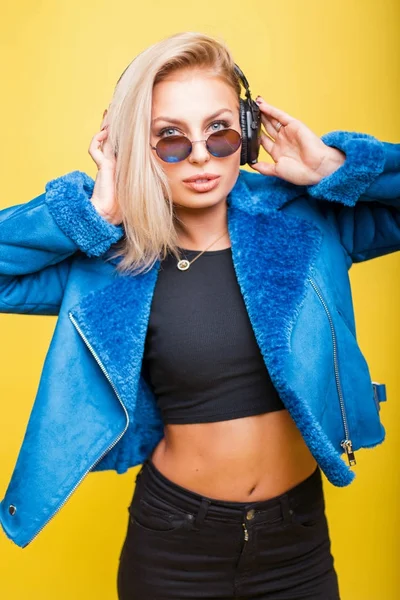 아름 다운 유행 젊은 여자 헤드폰 라운드 노란색 배경에 모피와 파란 재킷에 빈티지 선글라스 — 스톡 사진