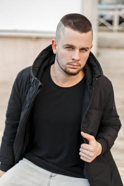 Retrato de um cara bonito jovem em uma jaqueta preta de inverno na rua — Fotografia de Stock