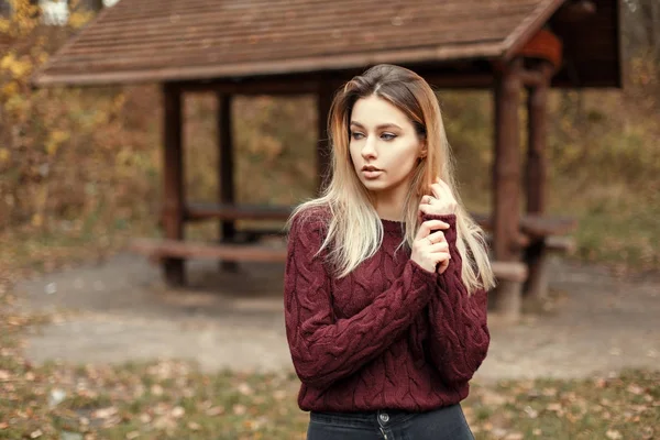 Bella donna bionda alla moda in un elegante maglione vintage lavorato a maglia in natura vicino a una casa di legno — Foto Stock