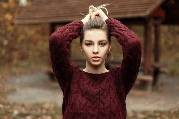 Stylische schöne junge Model-Mädchen in einem Vintage-Pullover hält ihr Haar auf der Natur — Stockfoto