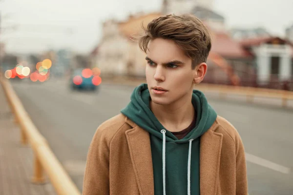 Retrato de un joven guapo con un corte de pelo en un abrigo de moda vintage en la calle — Foto de Stock