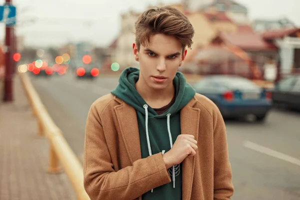 Portrait d'un jeune homme beau dans un manteau élégant à la mode dans la rue — Photo