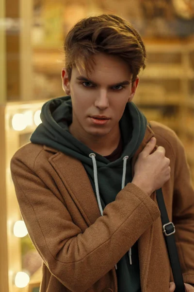 Fashion portrait of a young guy with a hairdo in a trendy coat on the street — Stock Photo, Image