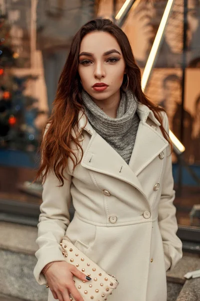 Jeune belle femme dans un manteau d'automne de mode avec un sac design élégant posant dans la rue — Photo