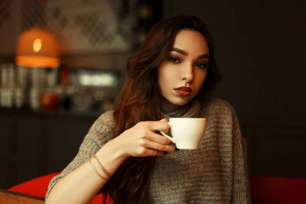 Belle jeune fille en pull tricoté avec une tasse de café reposant dans un café — Photo