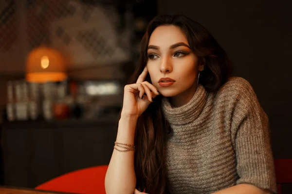 Jeune belle femme dans un pull tricoté élégant se trouve dans un café et rêve — Photo