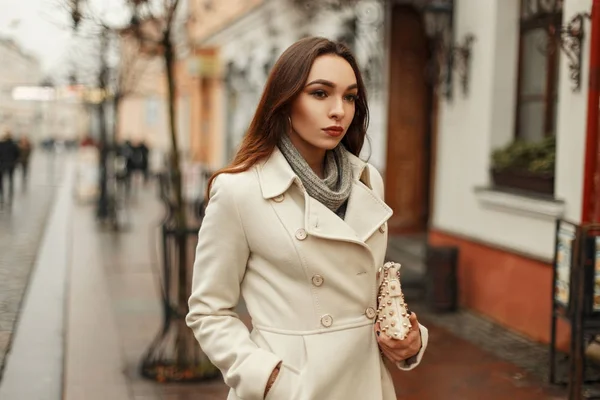 Jeune femme élégante en manteau d'automne à la mode avec sac à main marchant à l'extérieur dans la ville — Photo