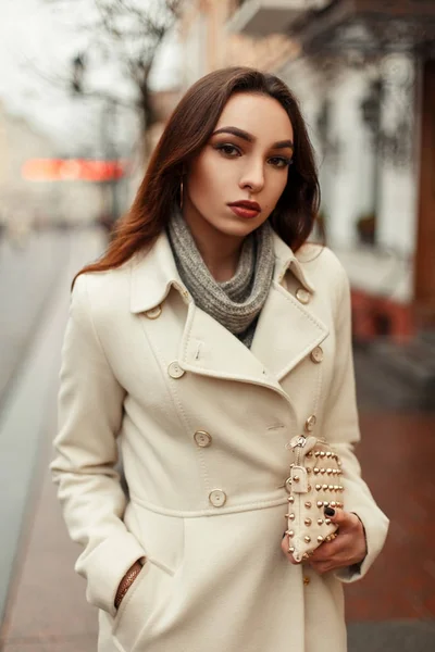 Jovem mulher moderna elegante em um casaco da moda com um saco de moda elegante em um dia de inverno na cidade — Fotografia de Stock