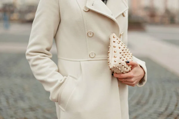 Välklätt mode handväska i en hand. Fashionabla kvinna i en kappa håller en väska — Stockfoto