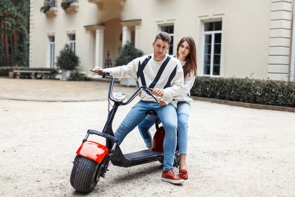 Belo casal apaixonado por roupas de moda elegantes andando de bicicleta eletrônica perto do hotel — Fotografia de Stock