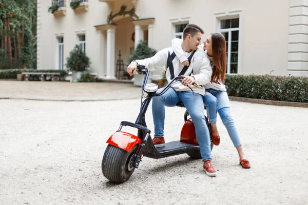 Knappe man van de modieuze en mooie jongedame in stijlvolle casual kleding op een elektrische fiets — Stockfoto