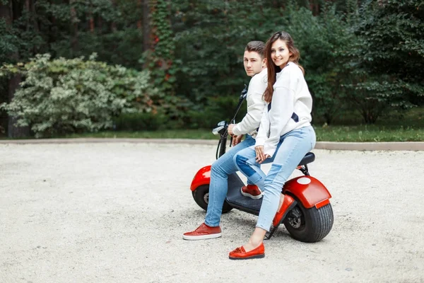 Όμορφο ζευγάρι σε επώνυμα κομψά ρούχα με ένα ηλεκτρικό ποδήλατο — Φωτογραφία Αρχείου