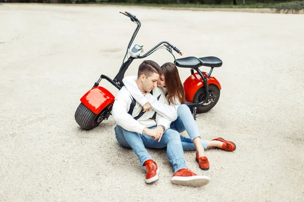 Mooie modieuze paar in stijlvolle denim casual kleding zitten in de buurt van electro fietsen — Stockfoto