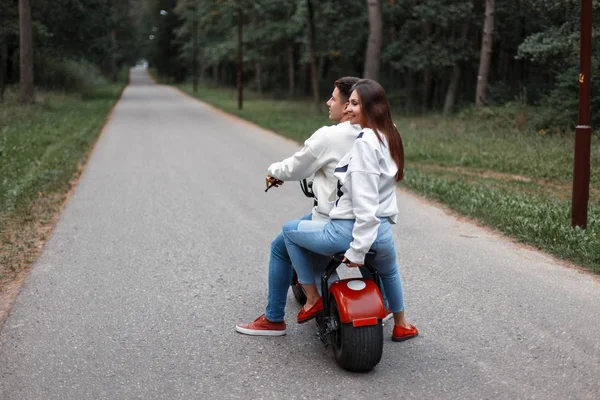 Hermosa pareja montando una bicicleta eléctrica en un bosque en la carretera — Foto de Stock