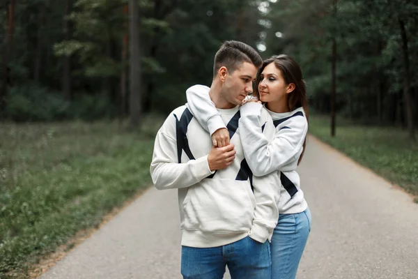 Belo par jovem em roupas brancas na moda com jeans abraçando na natureza — Fotografia de Stock