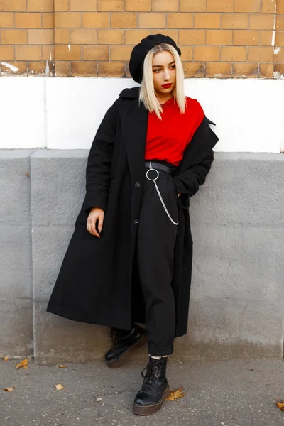 Hermosa mujer con estilo en un abrigo negro con una boina en zapatos posando cerca del edificio —  Fotos de Stock