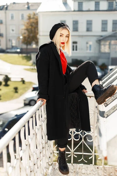 Mulher bonita com lábios vermelhos em um casaco de outono preto com uma boina em um dia ensolarado — Fotografia de Stock