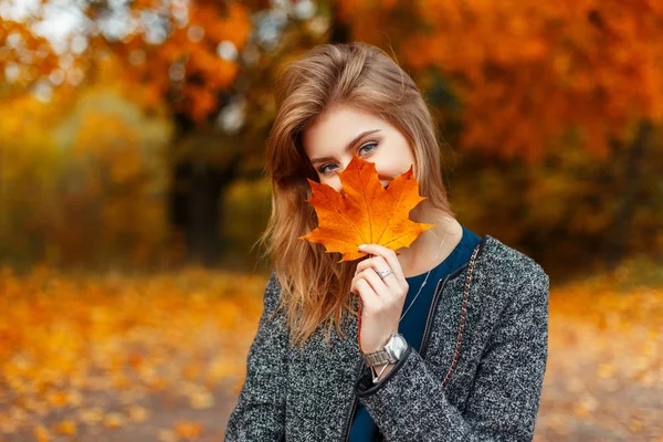 Giovane donna felice con una bella foglia gialla colorata godendo la giornata autunnale Foto Stock Royalty Free