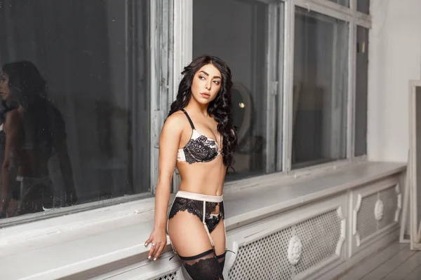 Schöne junge Frau in sexy Unterwäsche bei Fenstern drinnen — Stockfoto