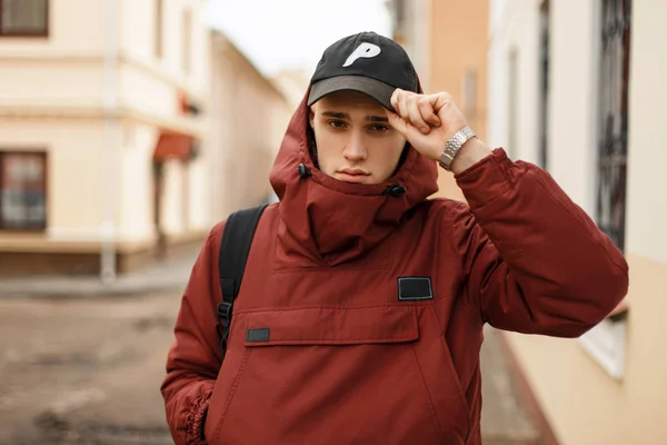 Joven de moda en una chaqueta elegante roja con un anuncio de mochila — Foto de Stock