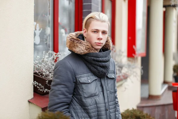 Jovem bonito com um corte de cabelo em uma jaqueta de inverno com uma malha — Fotografia de Stock